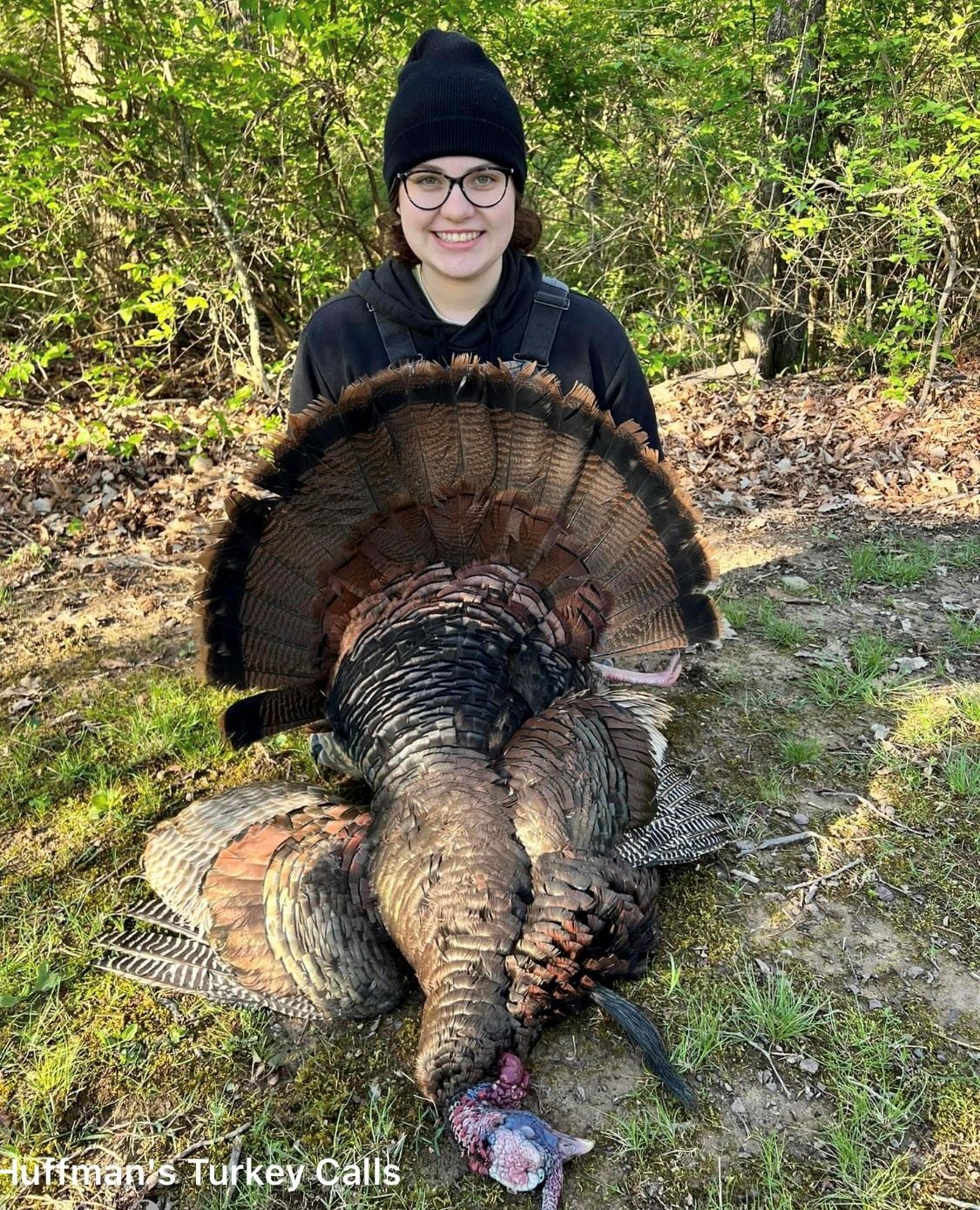 person holding a turkey in the woods